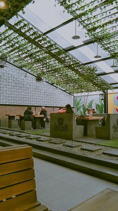 an indoor dining area with benches, tables and green plants hanging from the rafters