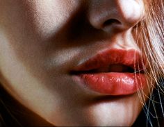 a close up of a woman's face with her hair blowing in the wind