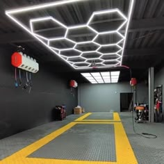 an empty room with yellow lines on the floor and lights hanging from the ceiling above