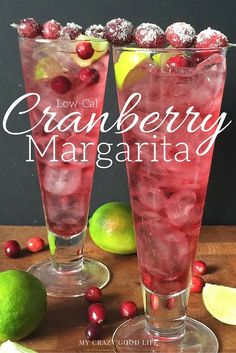 two tall glasses filled with cranberry margaritas on top of a wooden table