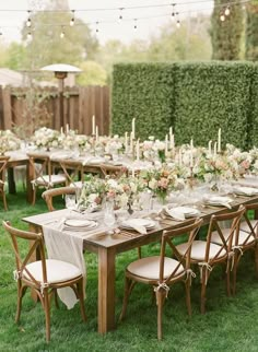 a long table set up with white flowers and greenery for an outdoor wedding reception