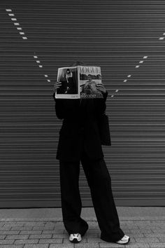 a person standing in front of a wall holding a magazine