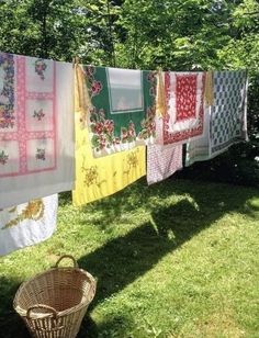 some towels are hanging on a clothes line outside in the grass with a basket next to it