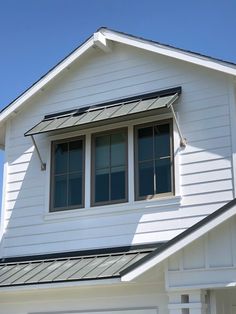 a white house with two windows and a black metal gutter on the front porch