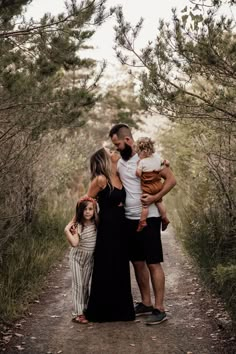 a group of people that are standing on a dirt road with trees in the background