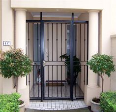 a gated entrance to a building with potted plants