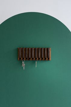 a green wall with two keys hanging from it