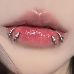 a woman's lips with three metal spikes on the top of her lip and bottom of her mouth