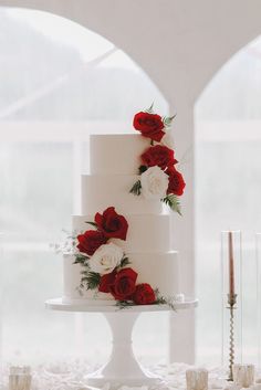 a white wedding cake with red and white flowers