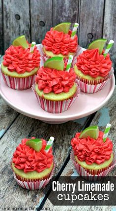 cupcakes decorated with red and green icing on a pink plate next to a wooden background