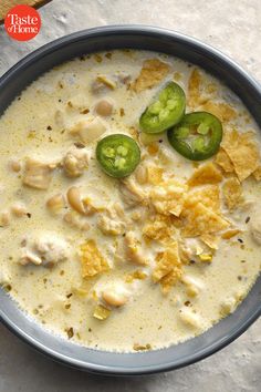 a blue bowl filled with chicken and tortilla soup on top of a table