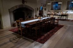 a dining room table and chairs in front of a fireplace with an area rug on the floor