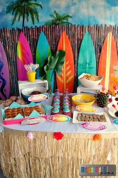 a table topped with lots of surfboards next to a wall covered in palm trees