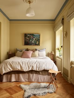 a bed sitting in a bedroom on top of a hard wood floor next to a window