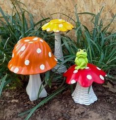 two small toad figurines sitting on top of grass next to each other in front of a stone wall