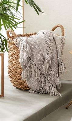 a woven basket sitting on top of a table next to a potted palm tree