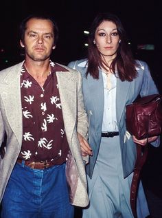 a man and woman walking down the street at night with one carrying a purse in his hand