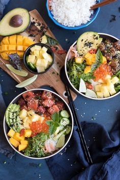 two bowls filled with different types of food on top of a blue table cloth next to chopsticks