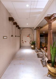 a long hallway with potted plants on either side and decorative wall hanging from the ceiling