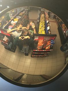 a fish eye lens view of people shopping in a grocery store, with the reflection of them making a heart shape