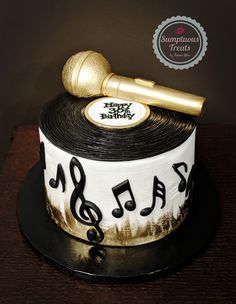 a birthday cake decorated with musical notes and a golden microphone on top, sitting on a table