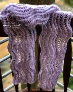 a purple knitted scarf sitting on top of a wooden chair