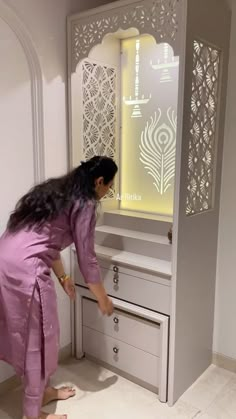 a woman standing in front of a cabinet with drawers and doors on the door way