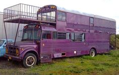 a purple bus parked in front of a building with a ladder on the top of it