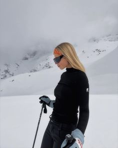 a woman standing on top of a snow covered slope wearing skis and goggles