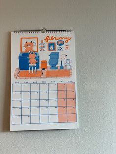 a calendar hanging on the wall with a cat and dog sitting in front of it