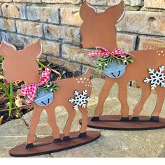 two wooden reindeers with snowflakes on their heads are standing in front of a brick wall