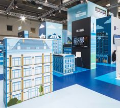 an exhibition stand with blue and white buildings on the floor in front of other displays