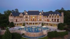 an aerial view of a large mansion with a pool in the front yard at dusk