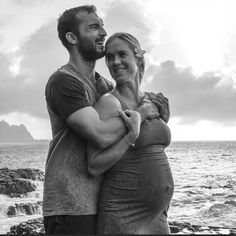 a man and woman hugging each other by the ocean