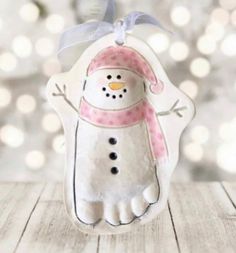 a white snowman ornament with a pink hat and scarf