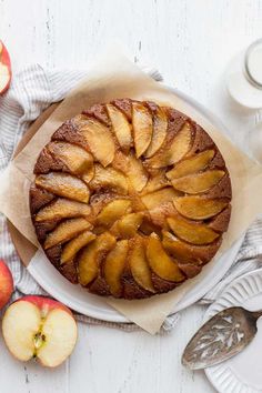 an apple cake on a plate with apples around it