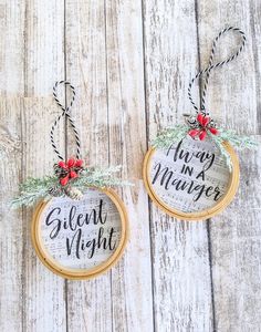 two christmas ornaments hanging on wooden boards with red berries and twine around the edges