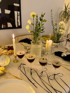 the table is set with glasses of wine and flowers in vases next to each other