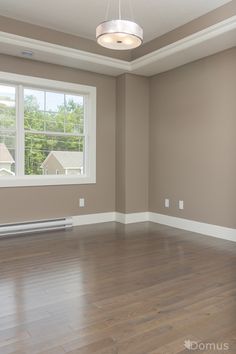 an empty room with hard wood flooring and a window in the corner that is open