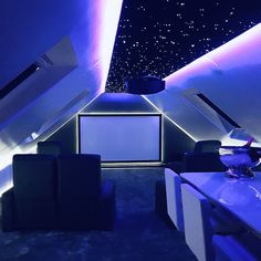 an empty room with blue lighting and white furniture in the center is lit up by stars on the ceiling