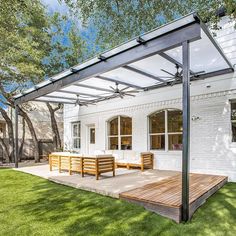 an outdoor patio with wooden benches under a pergolated roof