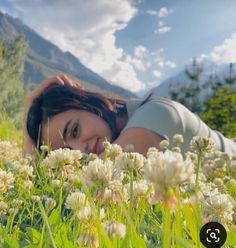 a woman laying in the grass with flowers around her