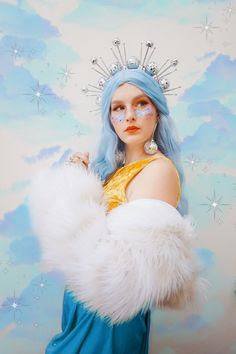 a woman with blue hair wearing a tiara and white fur stole around her shoulders