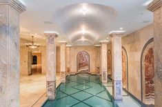 an indoor swimming pool with marble columns and tile flooring, surrounded by walls that have paintings on them