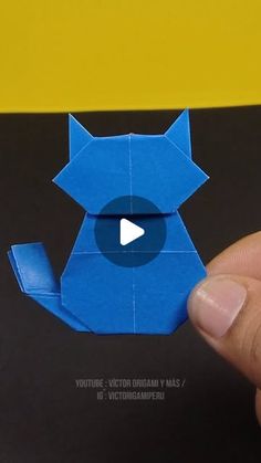 a hand holding an origami cat with a video playing button on the screen