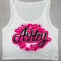 a white tank top with pink hearts and the word ashley in black letters on it