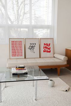 a living room with a couch, coffee table and two pictures on the window sill