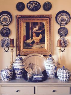 blue and white vases are sitting on a dresser in front of a framed painting