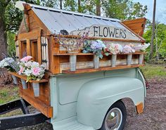 an old truck is decorated with flowers and other things on the bed, as if it were a flower shop