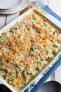 a casserole dish with broccoli and cheese on top sitting on a table